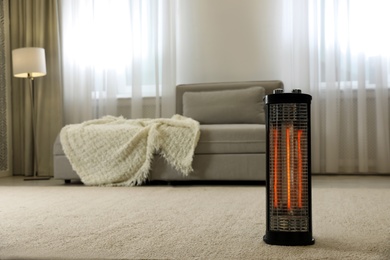 Photo of Modern electric halogen heater on floor in living room interior