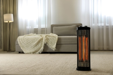 Modern electric halogen heater on floor in living room interior