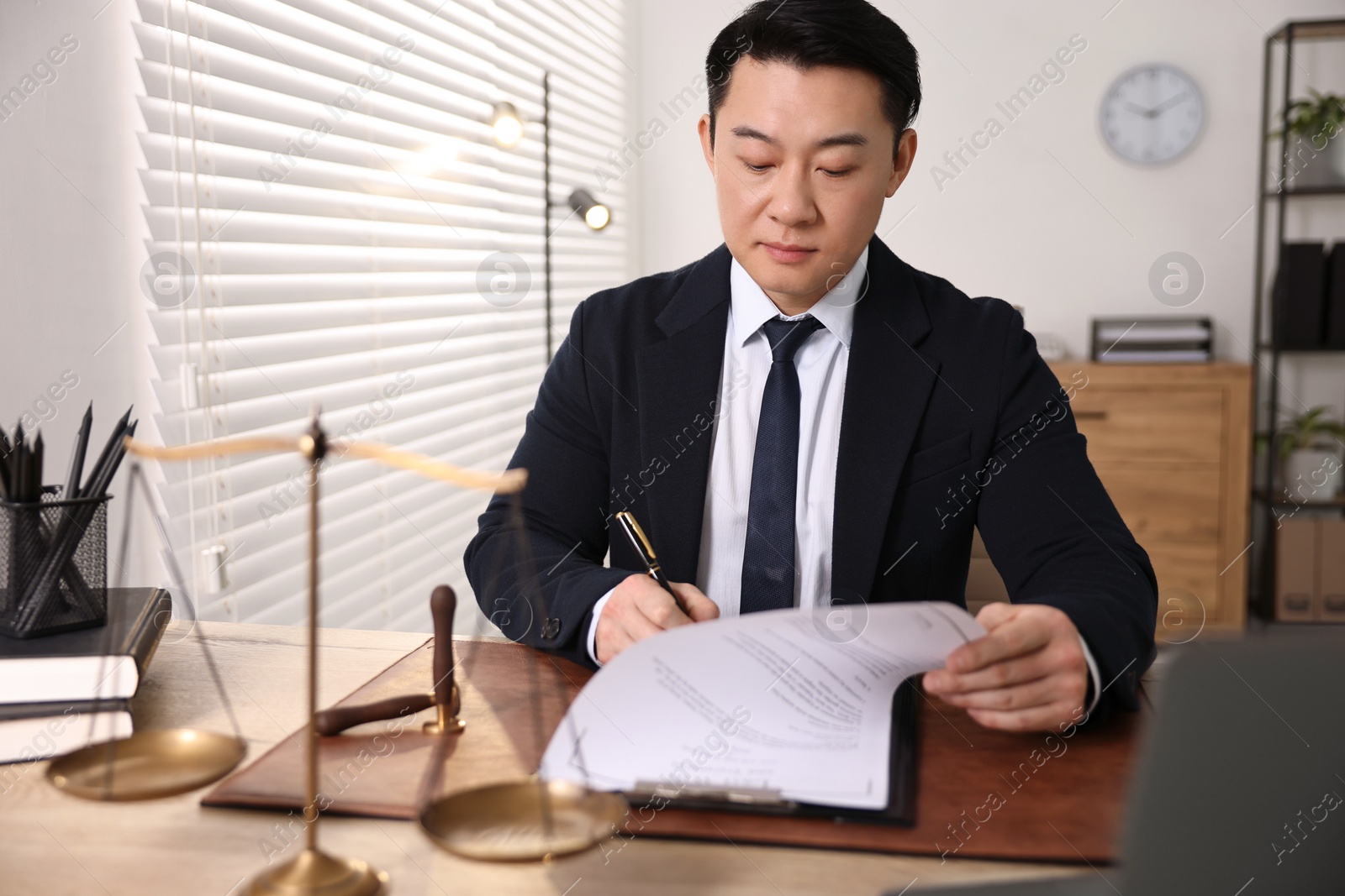 Photo of Notary writing notes at wooden table in office