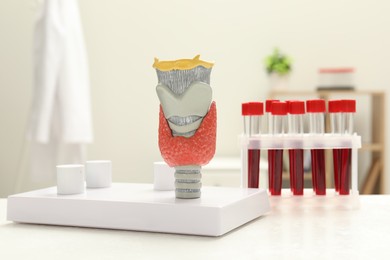 Endocrinology. Model of thyroid gland and samples of blood in test tubes on white table at clinic