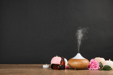 Photo of Composition with essential oils diffuser on table against black background. Space for text