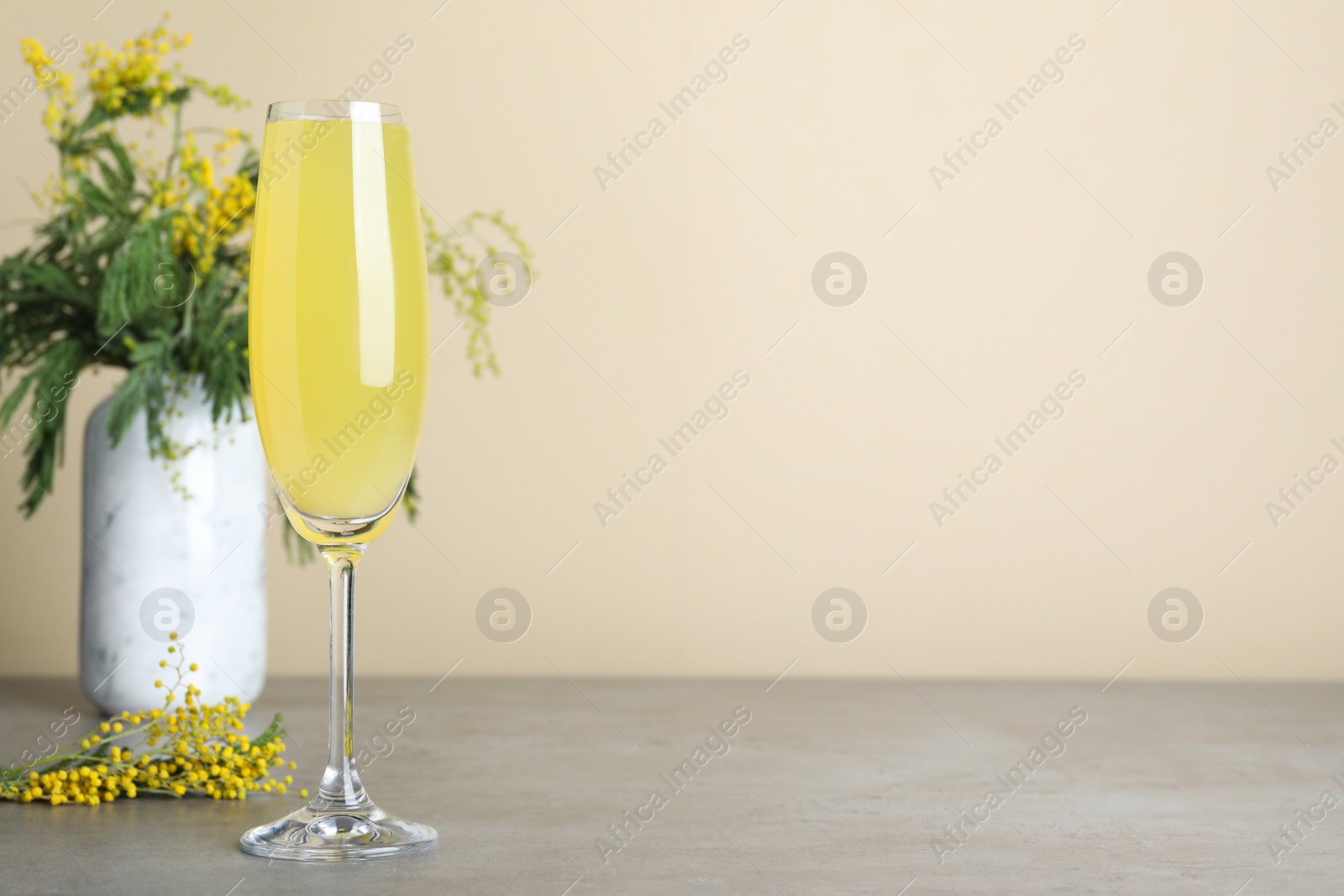 Photo of Glass of Mimosa cocktail on grey table. Space for text