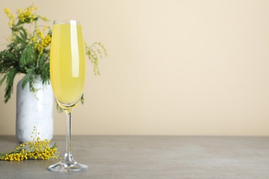 Photo of Glass of Mimosa cocktail on grey table. Space for text