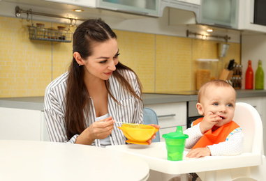 Young mother feeding her little baby at home