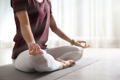 Woman practicing yoga on floor indoors, closeup. Space for text