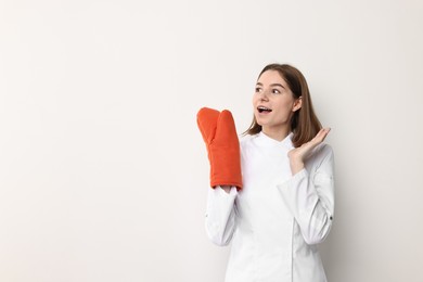 Photo of Professional chef with oven glove on light background. Space for text