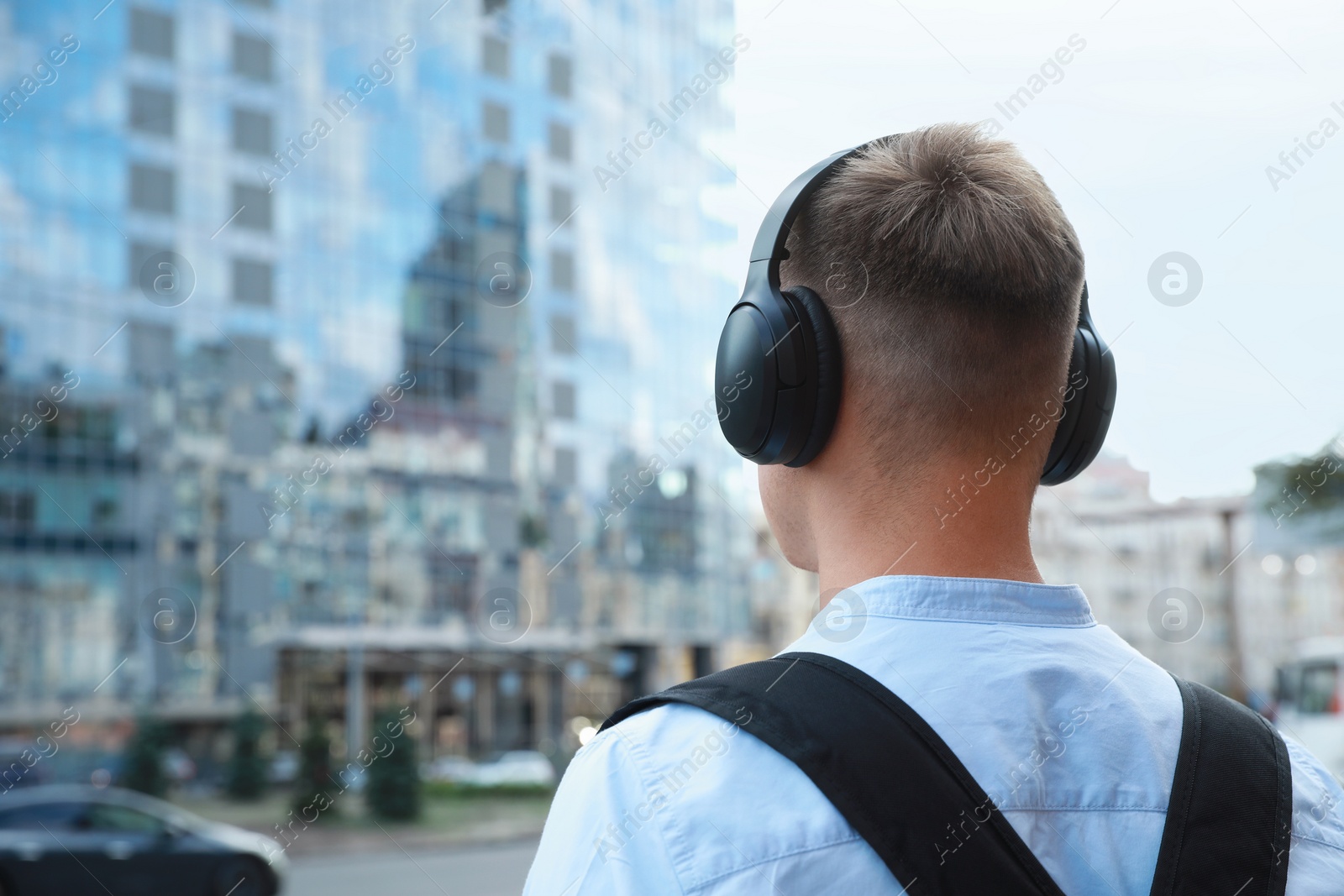 Photo of Man in headphones listening to music outdoors, back view. Space for text
