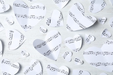 Paper hearts with music notes on white wooden background, flat lay