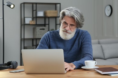 Photo of Middle aged man with laptop learning at table indoors