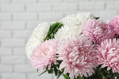 Photo of Beautiful aster flower bouquet near brick wall, closeup