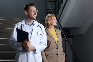Photo of Happy doctor with clipboard and patient in clinic