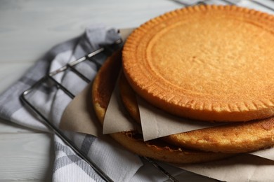 Photo of Delicious homemade sponge cakes with parchment on white wooden table, closeup