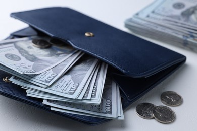 Photo of Dollar banknotes in wallet and coins on white table, closeup. Money exchange