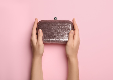 Photo of Woman holding small bag on pink background, top view