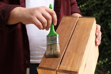 Photo of Man applying wood stain onto crate outdoors, closeup