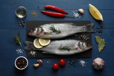 Photo of Flat lay composition with tasty sea bass fish and ingredients on blue wooden table
