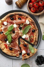 Photo of Tasty pizza with cured ham, olives, mozzarella cheese, tomatoes and basil on light tiled table, flat lay