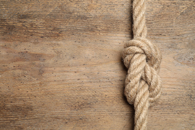 Photo of Top view of linen rope with knot on wooden background, space for text. Unity concept