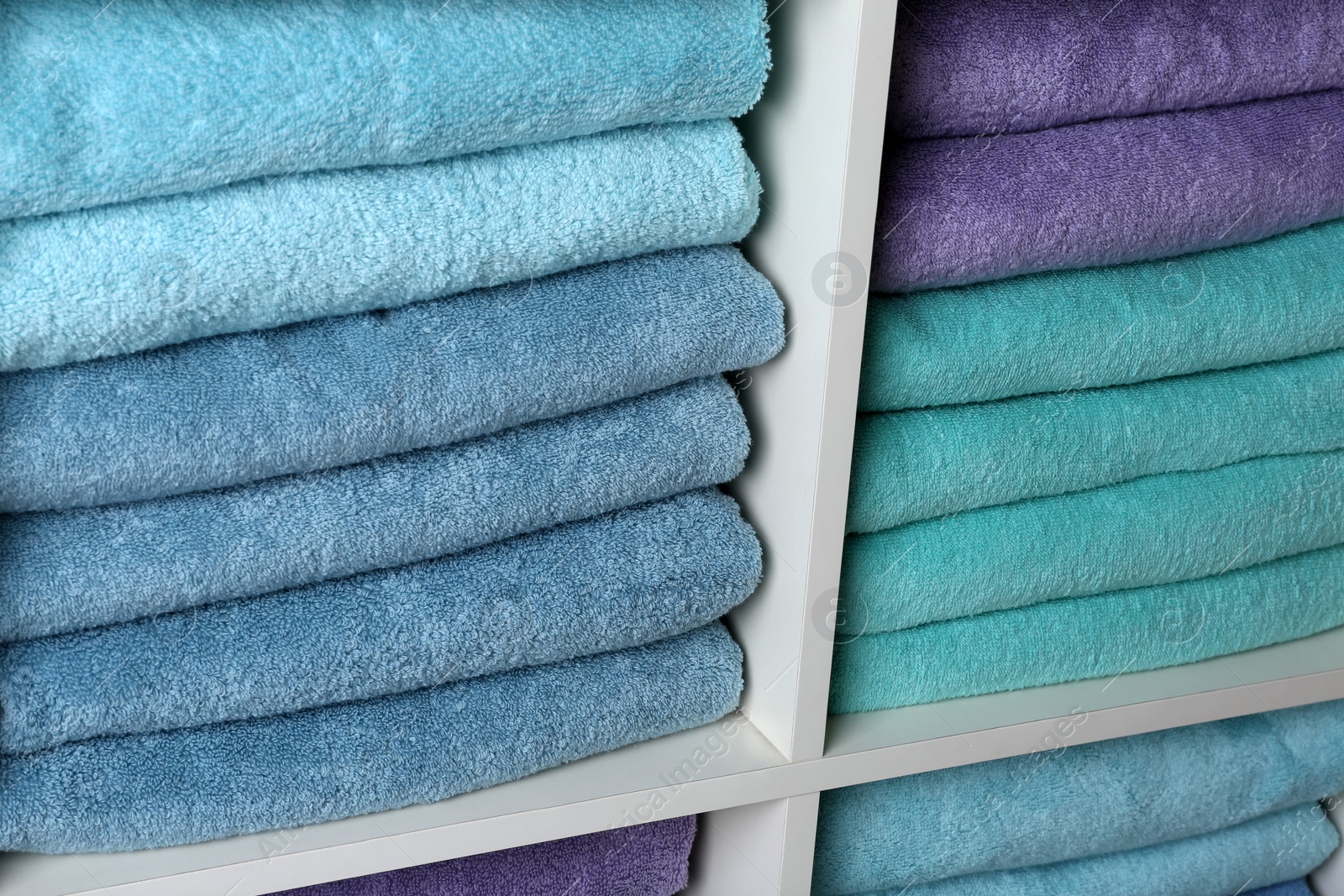 Photo of Colorful towels on shelves, closeup. Bathroom supplies