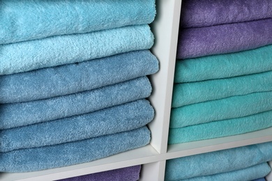 Photo of Colorful towels on shelves, closeup. Bathroom supplies