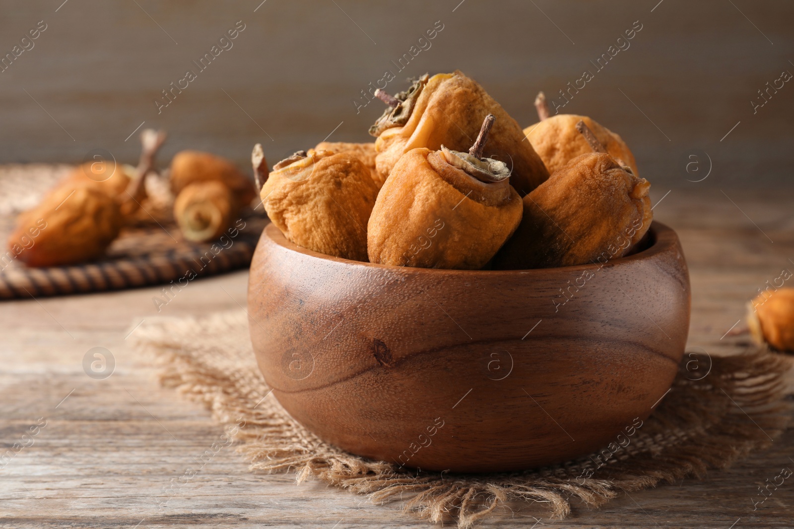 Photo of Bowl with tasty dried persimmon fruits on wooden table