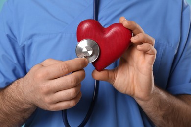 Photo of Doctor with stethoscope and red heart, closeup. Cardiology concept
