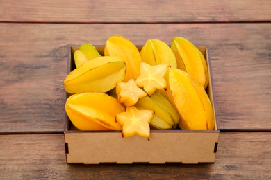 Cut and whole delicious ripe carambolas in box on wooden table