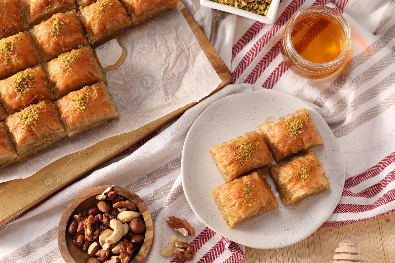 Photo of Delicious sweet baklava with nuts and honey on table, flat lay