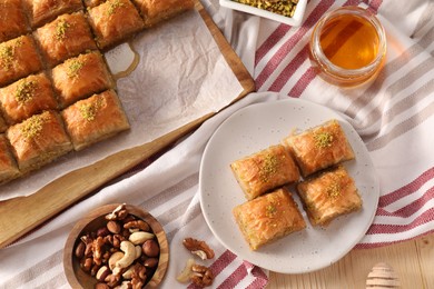Photo of Delicious sweet baklava with nuts and honey on table, flat lay