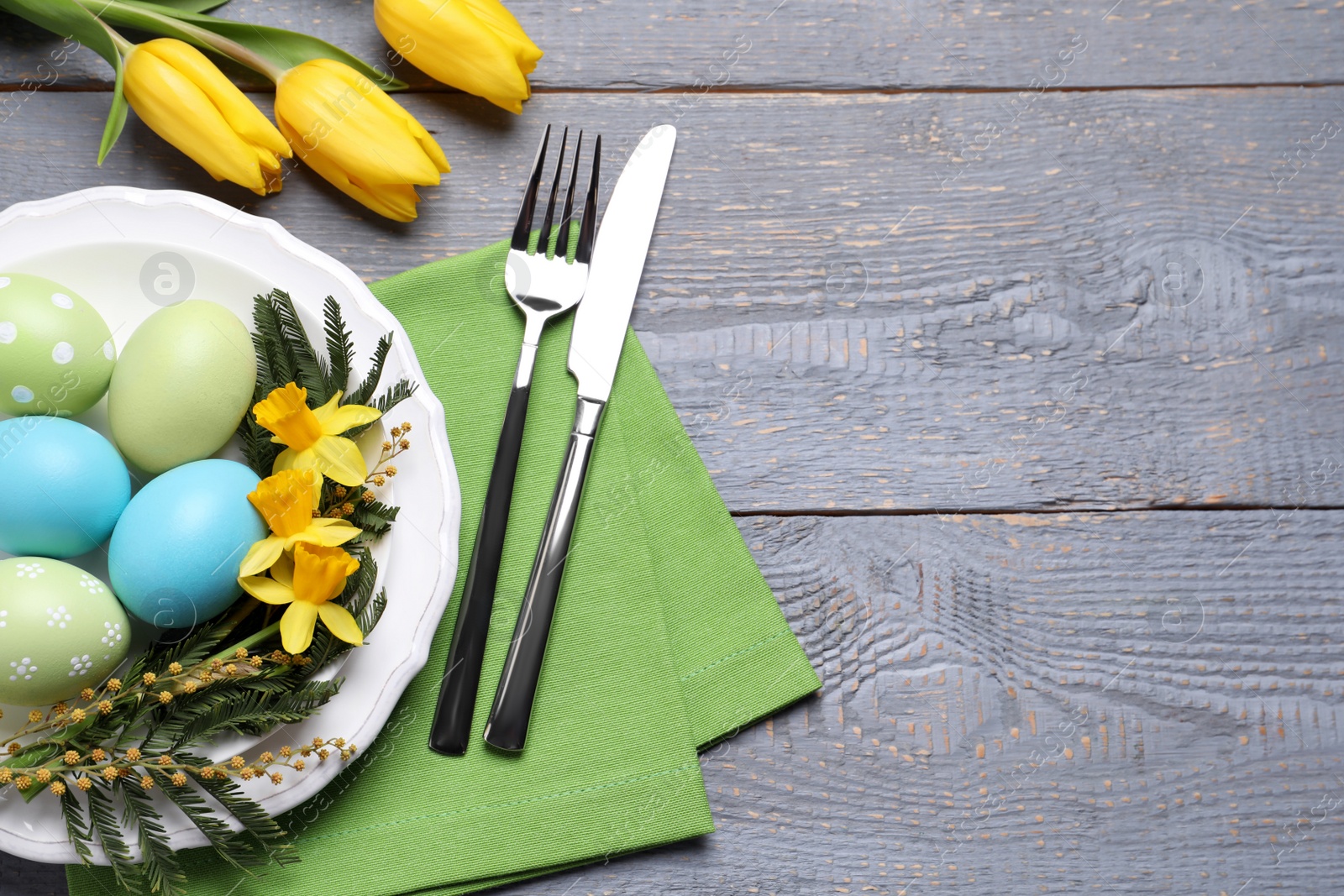 Photo of Festive Easter table setting with eggs on grey wooden background, flat lay. Space for text