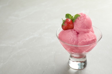 Photo of Delicious strawberry ice cream in dessert bowl on grey marble table, space for text
