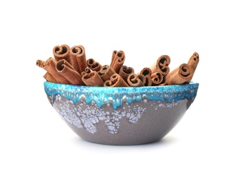 Photo of Bowl with aromatic cinnamon sticks on white background