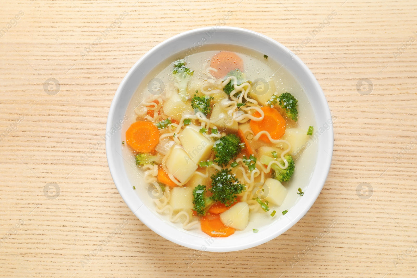 Photo of Bowl of fresh homemade vegetable soup on wooden background, top view