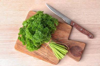 Board with fresh green parsley on wooden background, top view