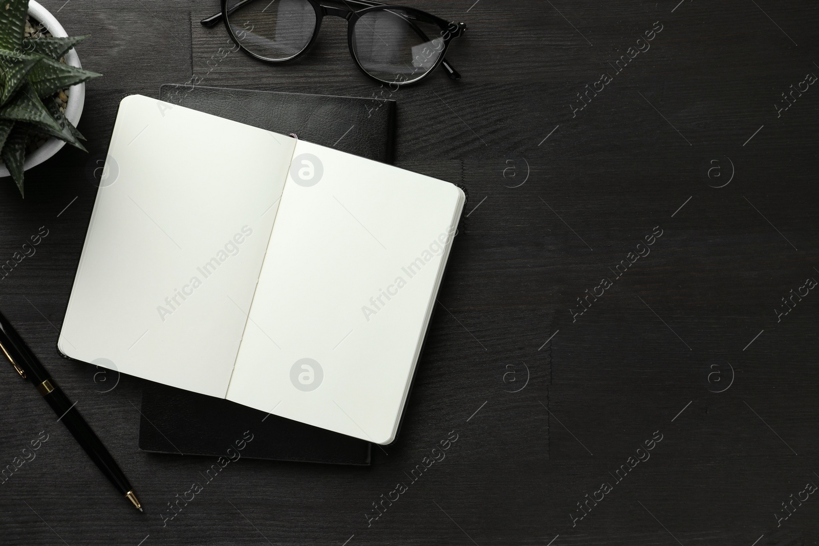 Photo of Flat lay composition with notebooks and pen on black wooden table. Space for text