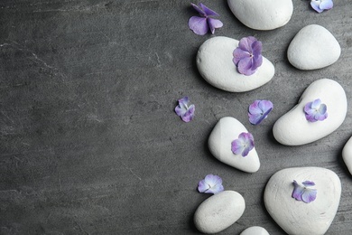 Zen stones and exotic flowers on dark background, top view with space for text