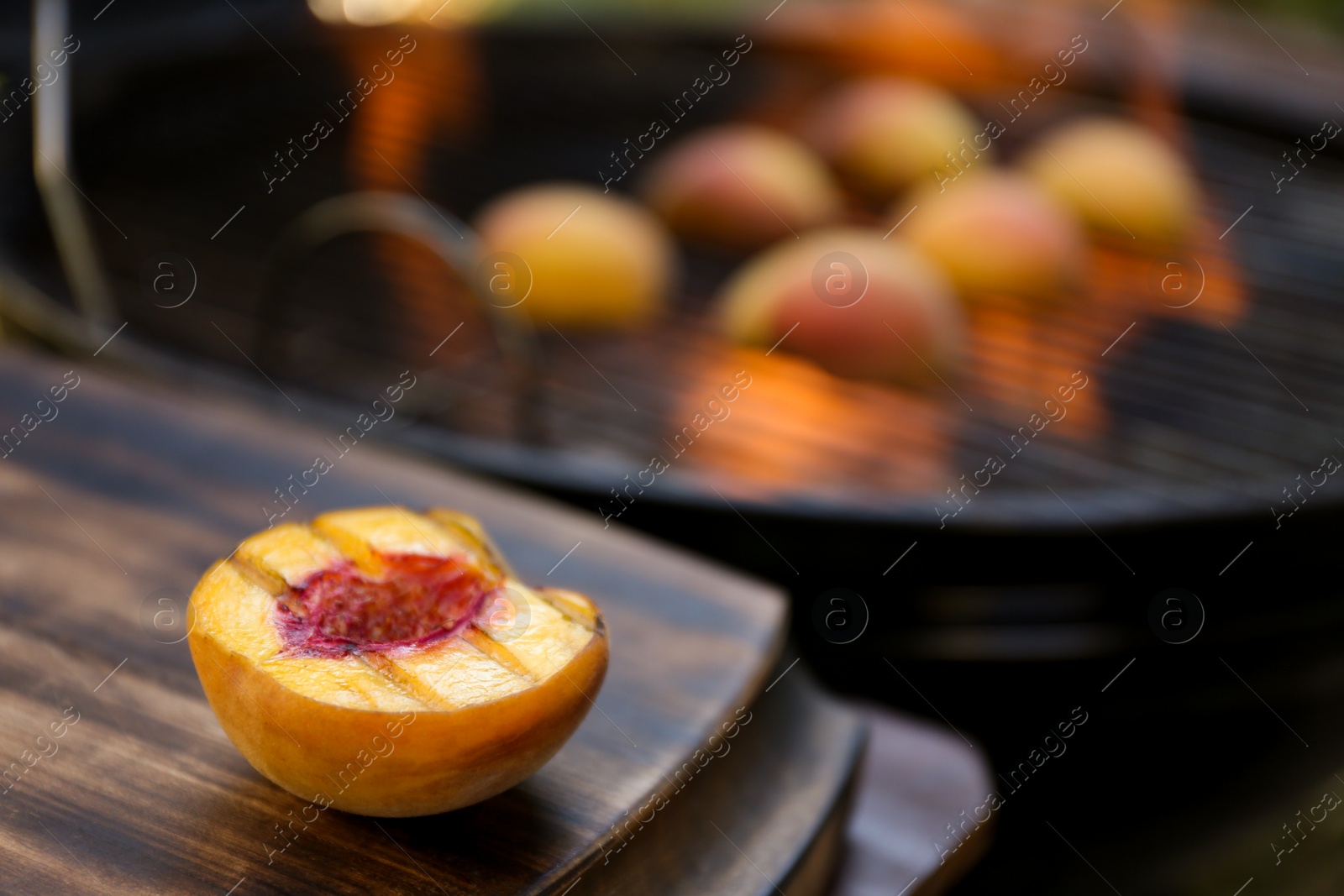 Photo of Half of delicious grilled peach on wooden table, closeup