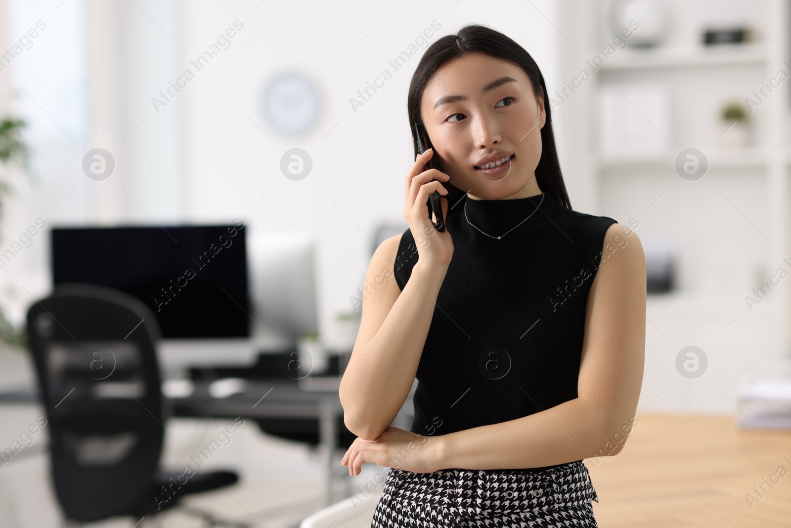 Photo of Portrait of smiling businesswoman talking on smartphone in office. Space for text