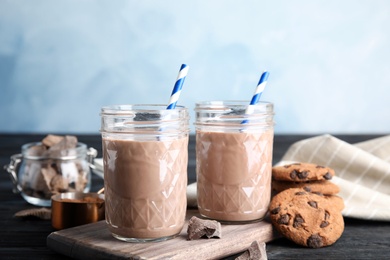 Jars with tasty chocolate milk on wooden table. Dairy drink