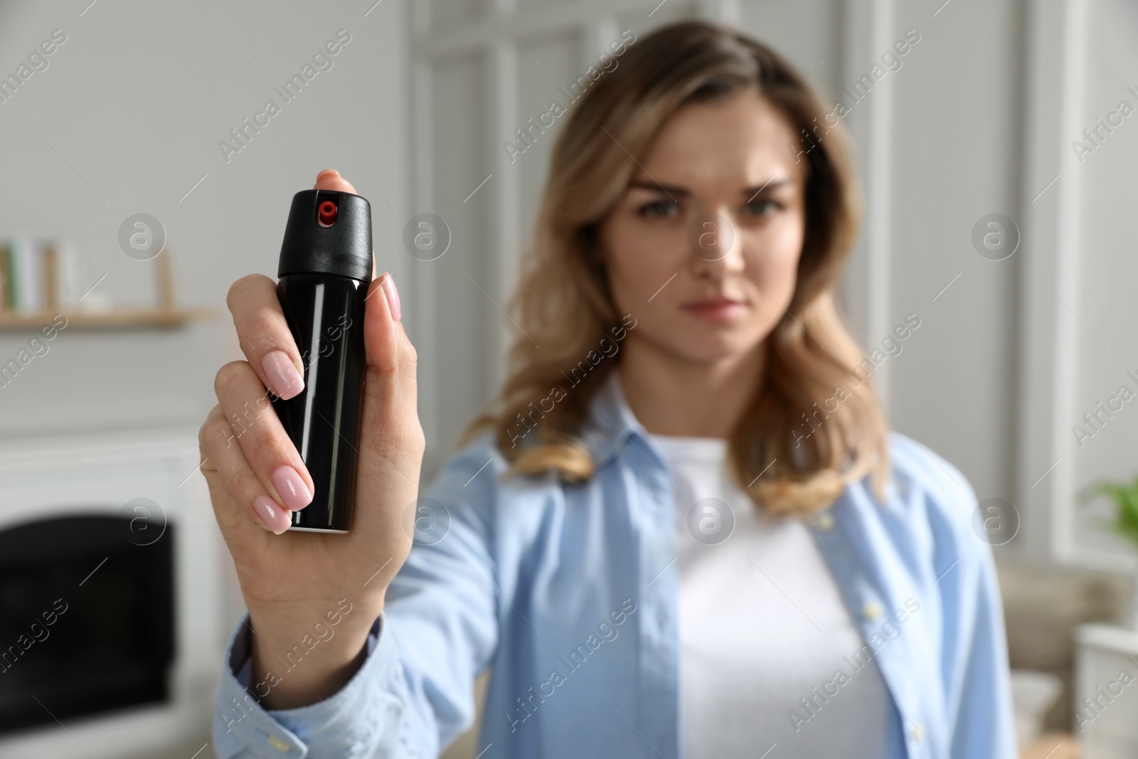 Photo of Young woman using pepper spray at home, focus on hand