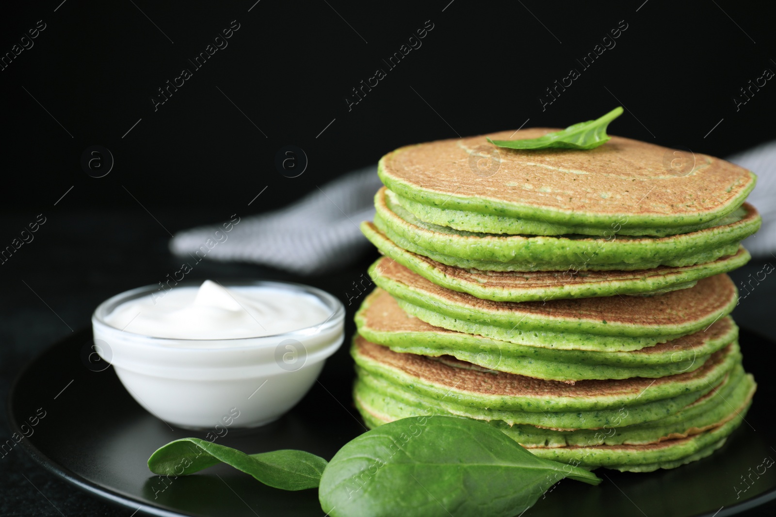 Photo of Tasty spinach pancakes on black table, closeup