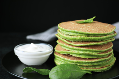 Photo of Tasty spinach pancakes on black table, closeup