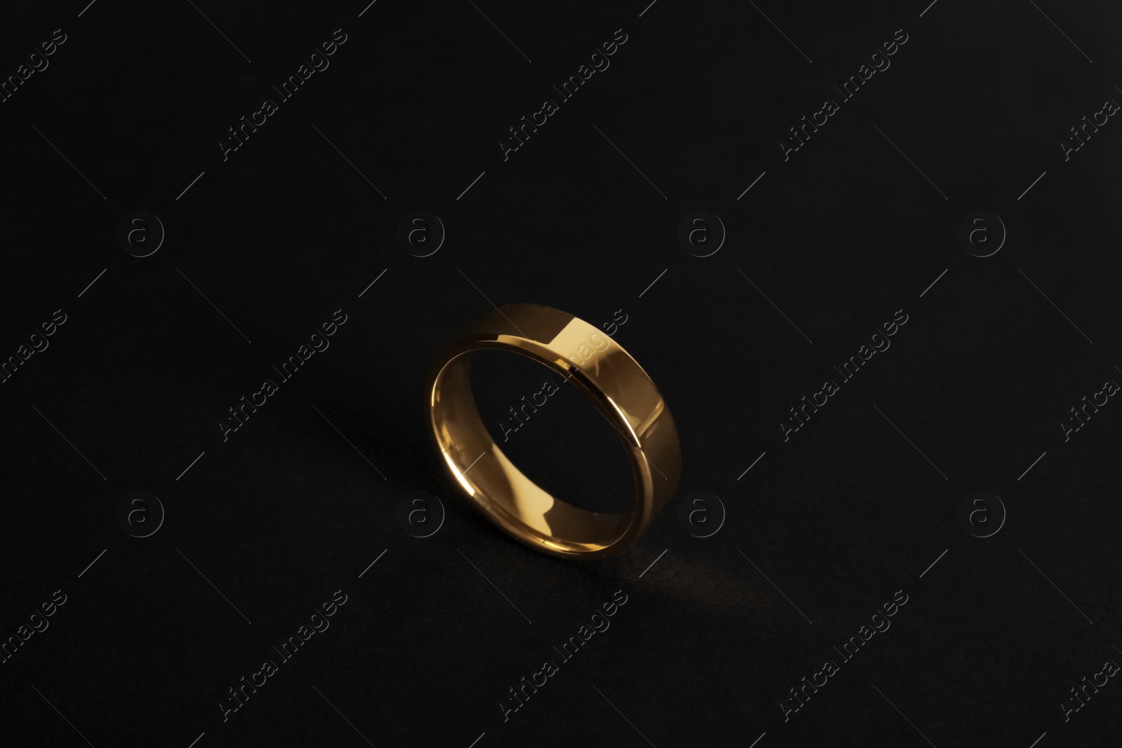 Photo of Beautiful gold wedding ring on black background