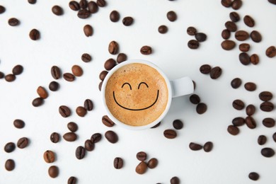 Good morning. Cup of tasty espresso and scattered coffee beans on white table, flat lay