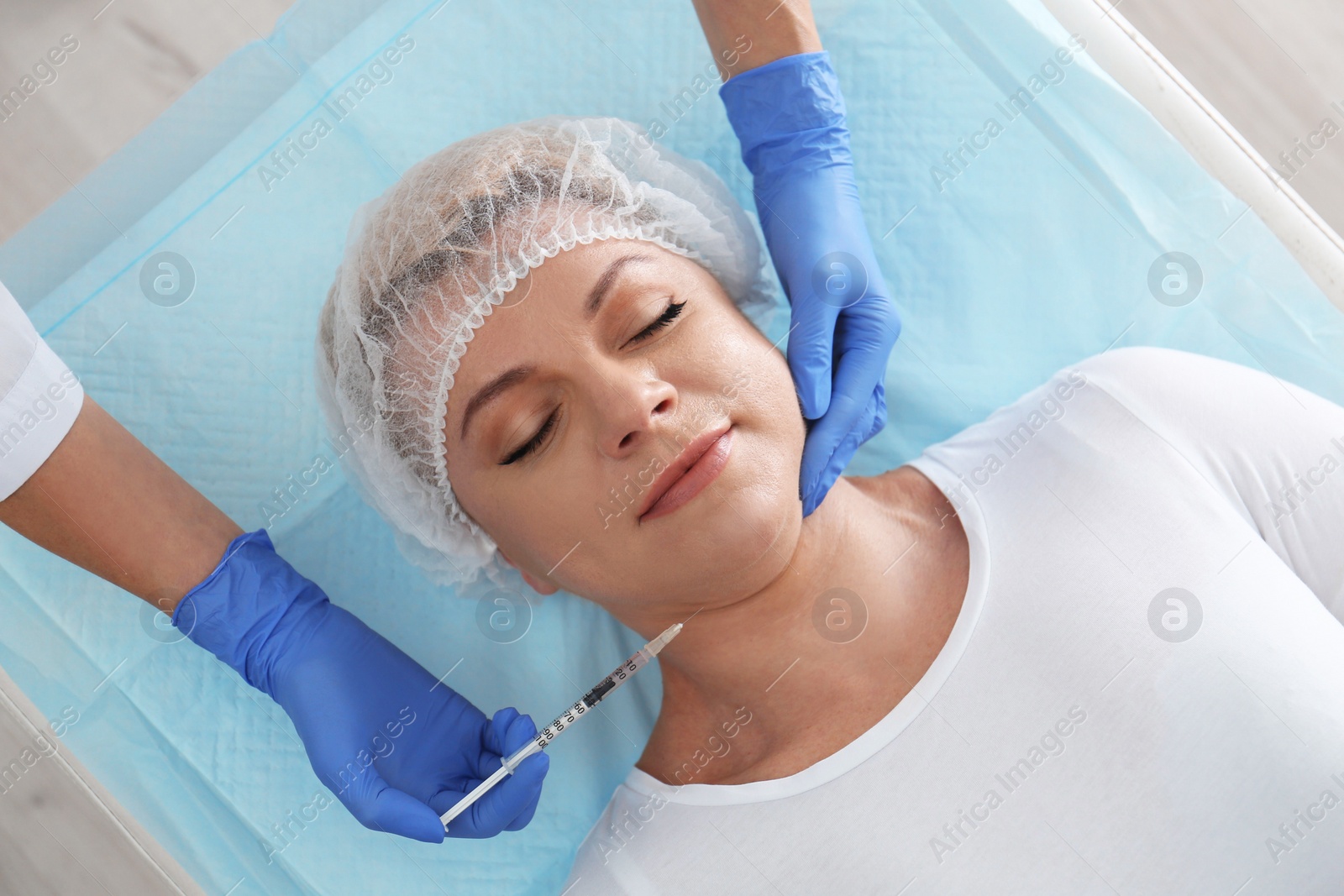 Photo of Mature woman with double chin receiving injection in clinic, above view