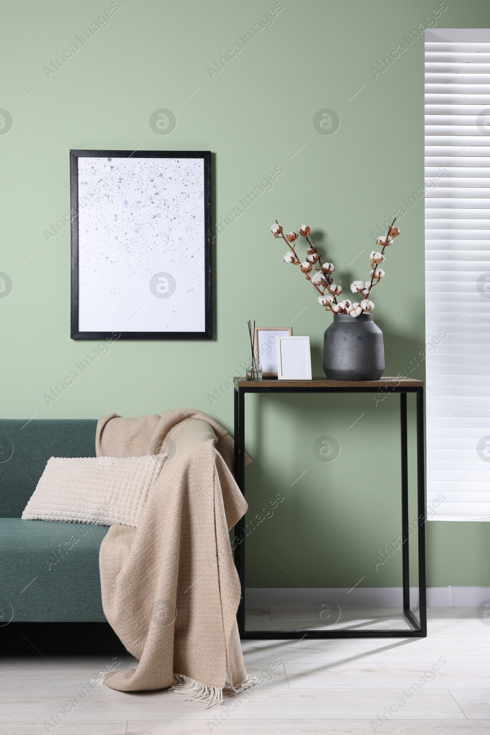 Photo of Branches with white fluffy cotton flowers on console table in cozy room. Interior design