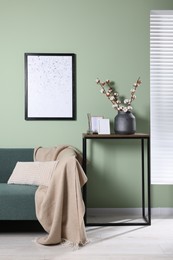 Photo of Branches with white fluffy cotton flowers on console table in cozy room. Interior design