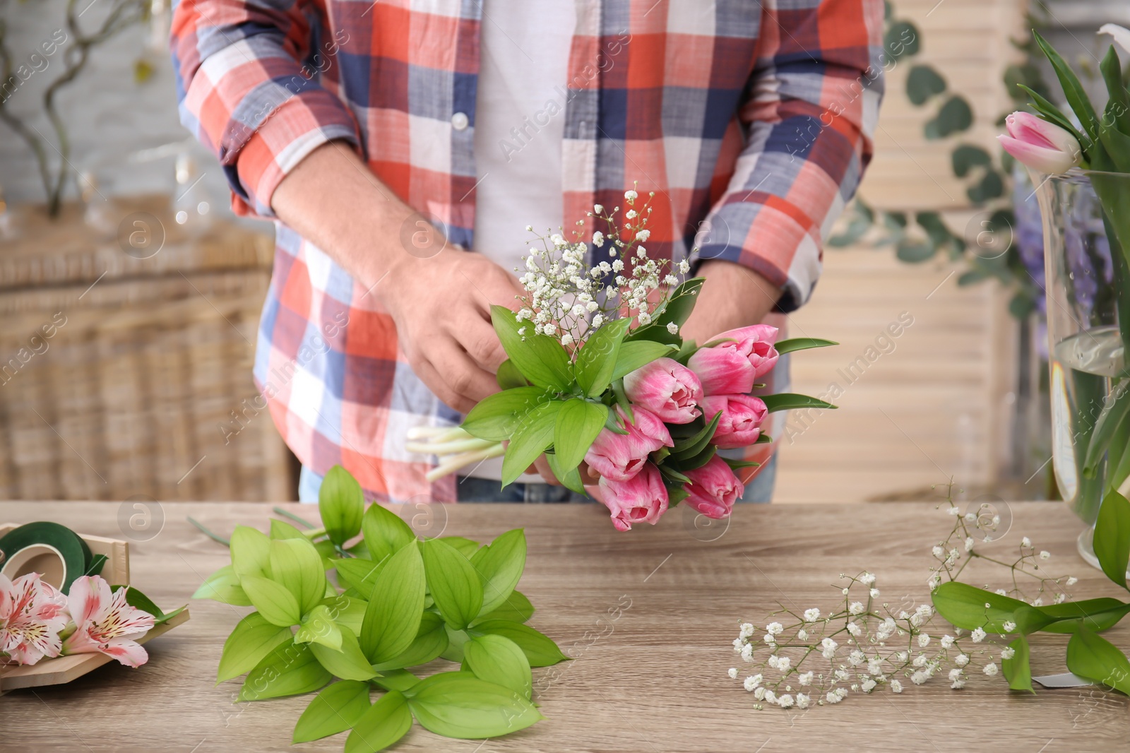 Photo of Male decorator creating beautiful bouquet at table