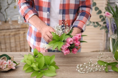 Male decorator creating beautiful bouquet at table