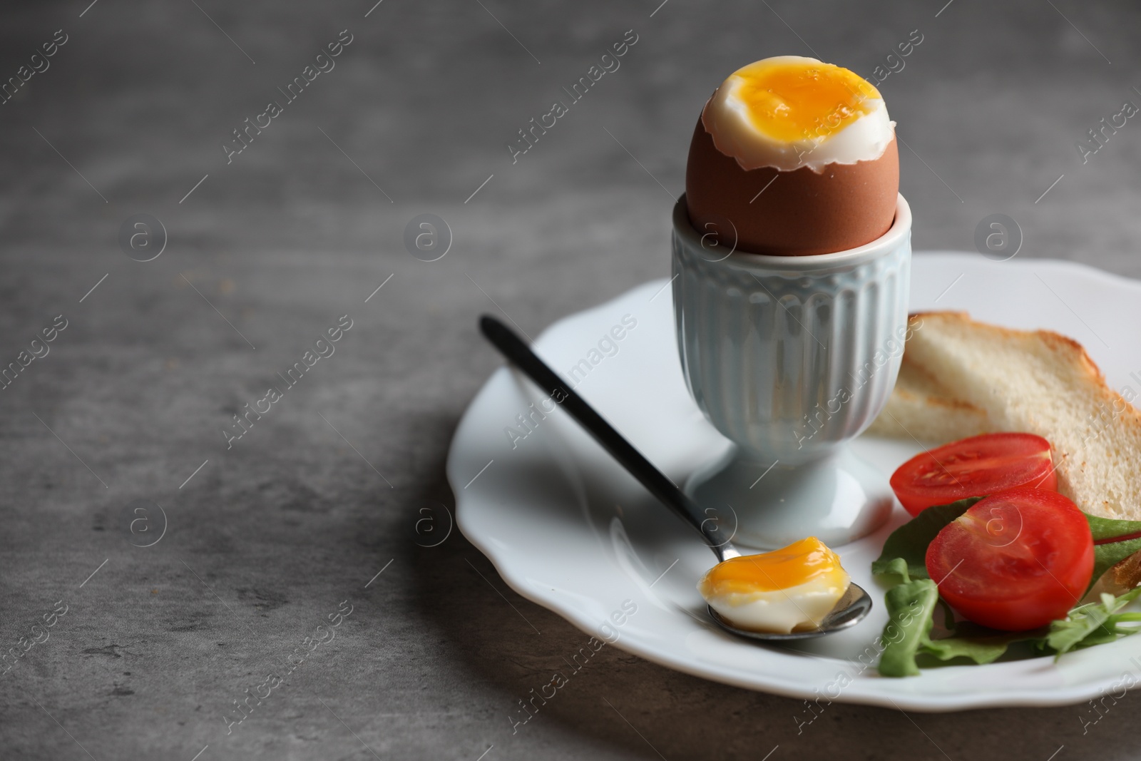 Photo of Delicious breakfast with soft boiled egg and fresh tomato served on grey table, closeup. Space for text